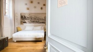 Quarto com cama, cabeceira com fotografia em preto e branco e um aviso na parede.