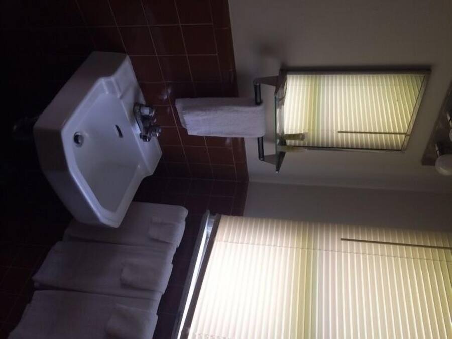 A bathroom with a sink, a toilet, and a window with blinds.