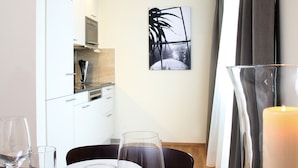 A dining area with a table set for four, including plates, glasses, and cutlery. A candle is on the table, and there is a kitchen visible in the background. - City Stay Seefeld House (Zürich)
