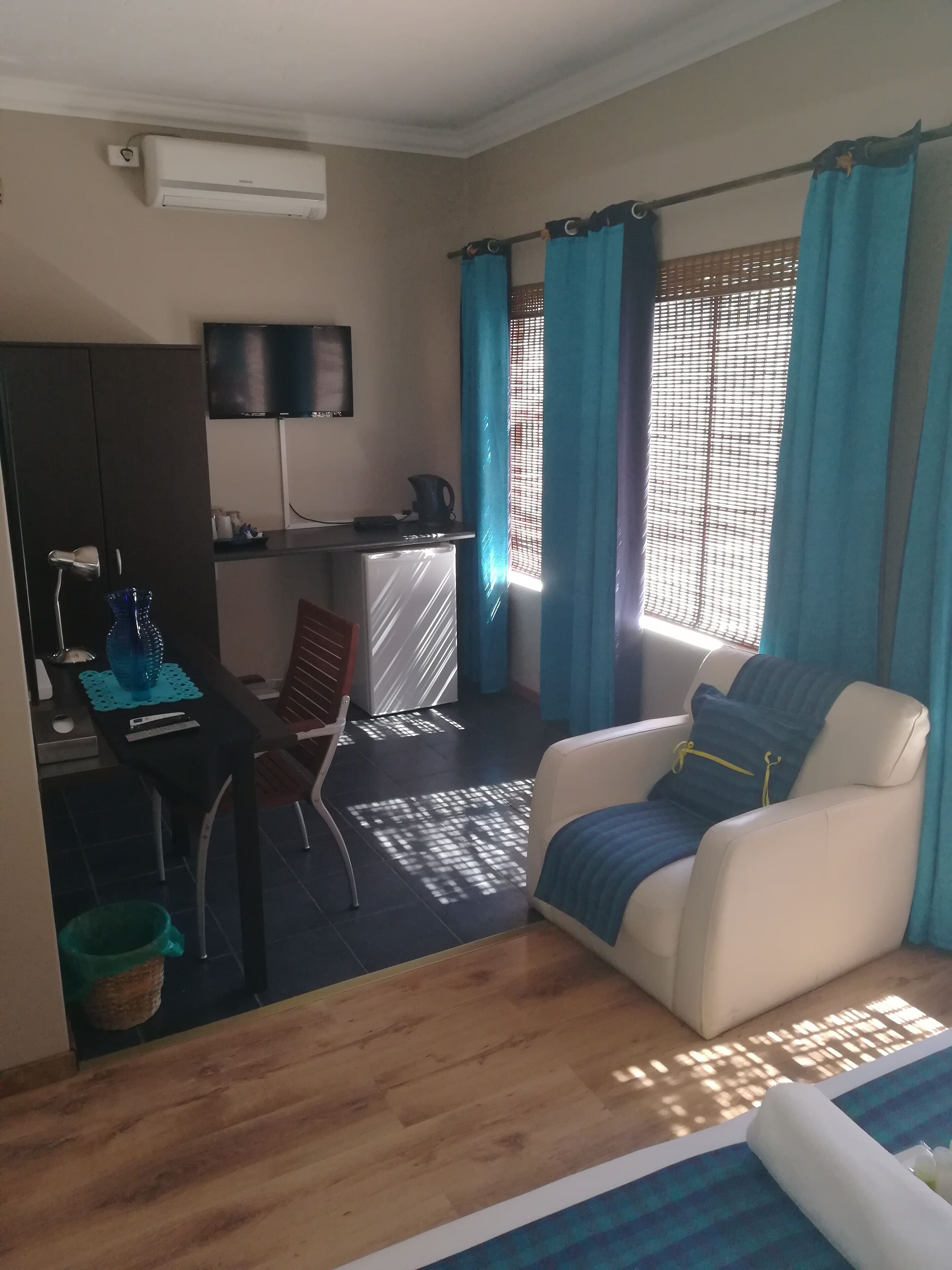 Un espacio habitable compacto con kitchenette, comedor y zona de estar con sofá y sillón.
