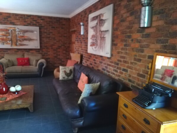 A living room with a brick wall, a leather sofa, a wooden coffee table, and a vintage typewriter.