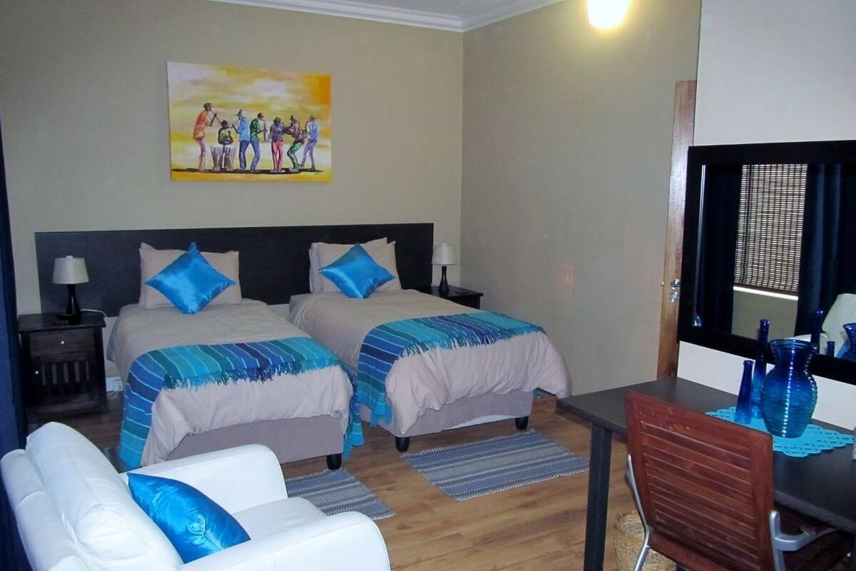Ein Hotelzimmer mit zwei Betten, einem Schlafsofa, einem Schreibtisch und einem Bild an der Wand.