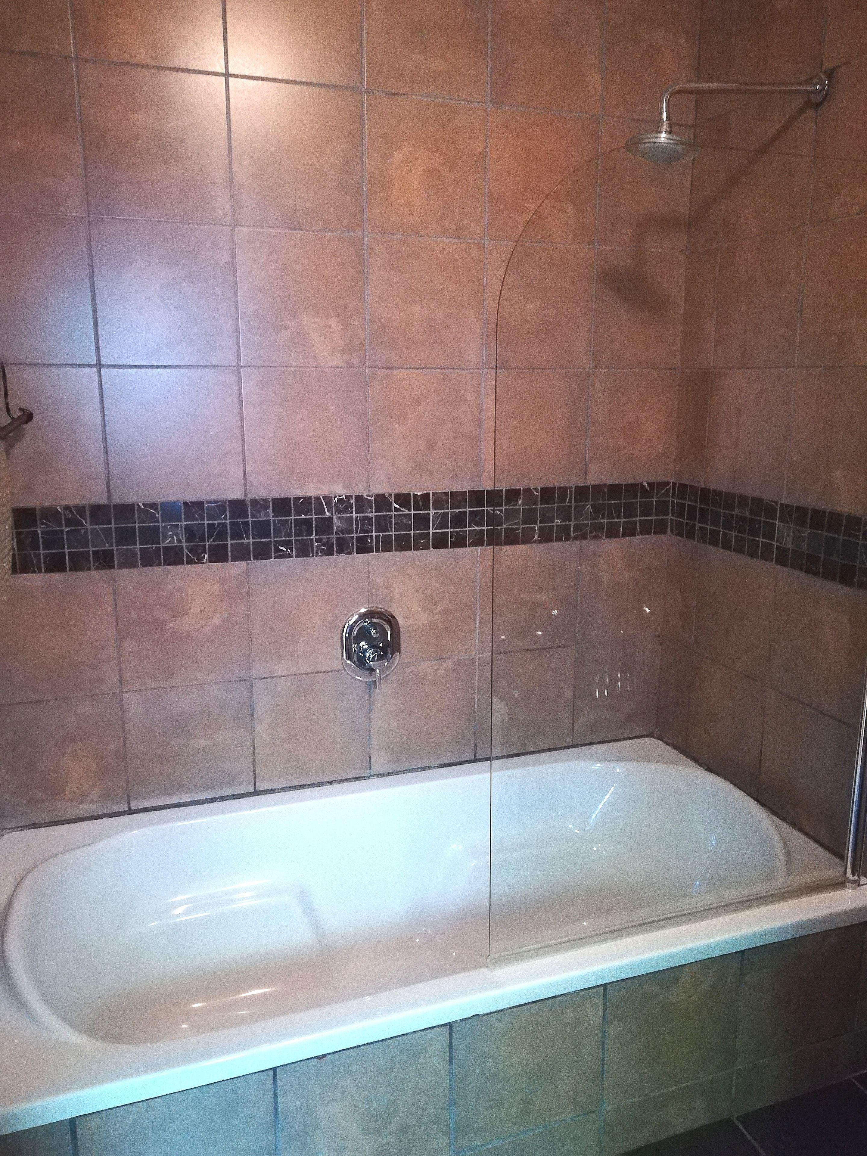 A bathroom with a bathtub, a shower, and a tiled wall.