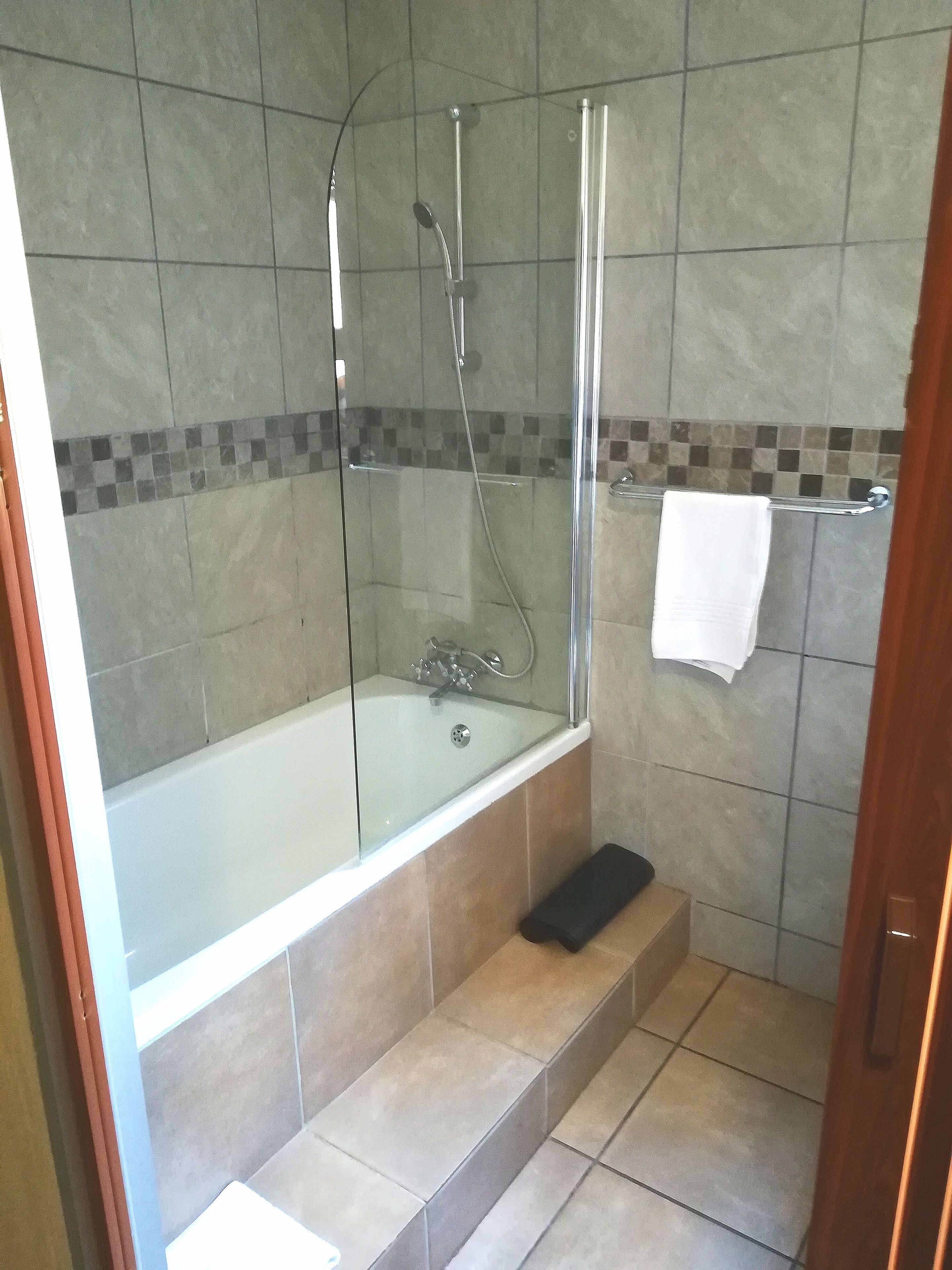 Ein modernes Badezimmer mit einer gläsernen Duschkabine, einer freistehenden Badewanne und einem Fliesenboden.