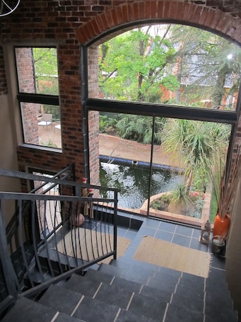 A staircase leading to a balcony with a view of a garden and a pond.