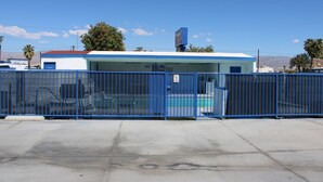 A motel with a blue exterior, fenced parking area, and a sign indicating it is a motel. - City Center Motel (Indio)