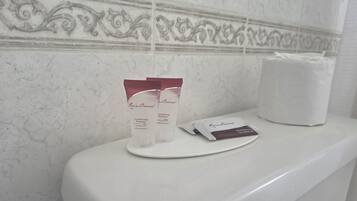 Un baño con pared de mármol, un inodoro blanco y una caja de pañuelos.
