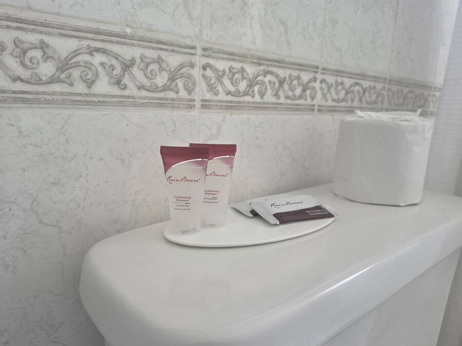 Un baño con pared de mármol, un inodoro blanco y una caja de pañuelos.