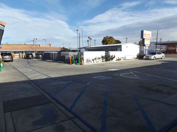 A parking lot with a motel sign, a gated entrance, and a few cars parked.