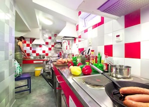 A modern kitchen with red and white checkered tiles, stainless steel appliances, and a variety of fresh vegetables on the counter.
