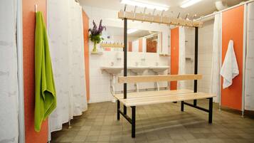 A bathroom with a bench, towel rack, sinks, and a mirror.