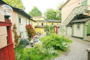A courtyard with a gravel path, surrounded by buildings with green and yellow facades, and a staircase leading to an upper level. - STF Zinkensdamm Hostel (Stockholm)