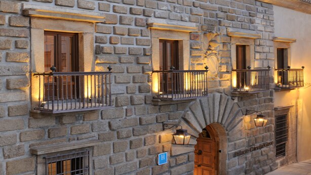 A stone building with multiple balconies, a wooden door, and a staircase leading to an upper level.