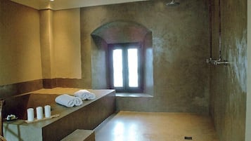 Experience a serene bathroom retreat with a large curved shower, bench, and natural light.