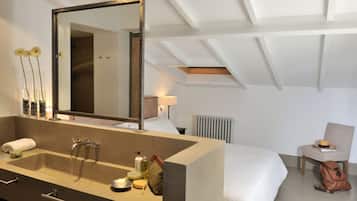 Una habitación de hotel moderna con un amplio tocador de baño, una cama, una silla y un radiador.