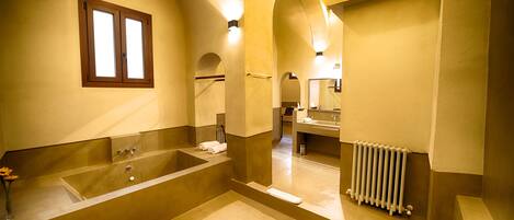 A spacious bathroom with a large bathtub, a separate shower area, and a vanity with a mirror.