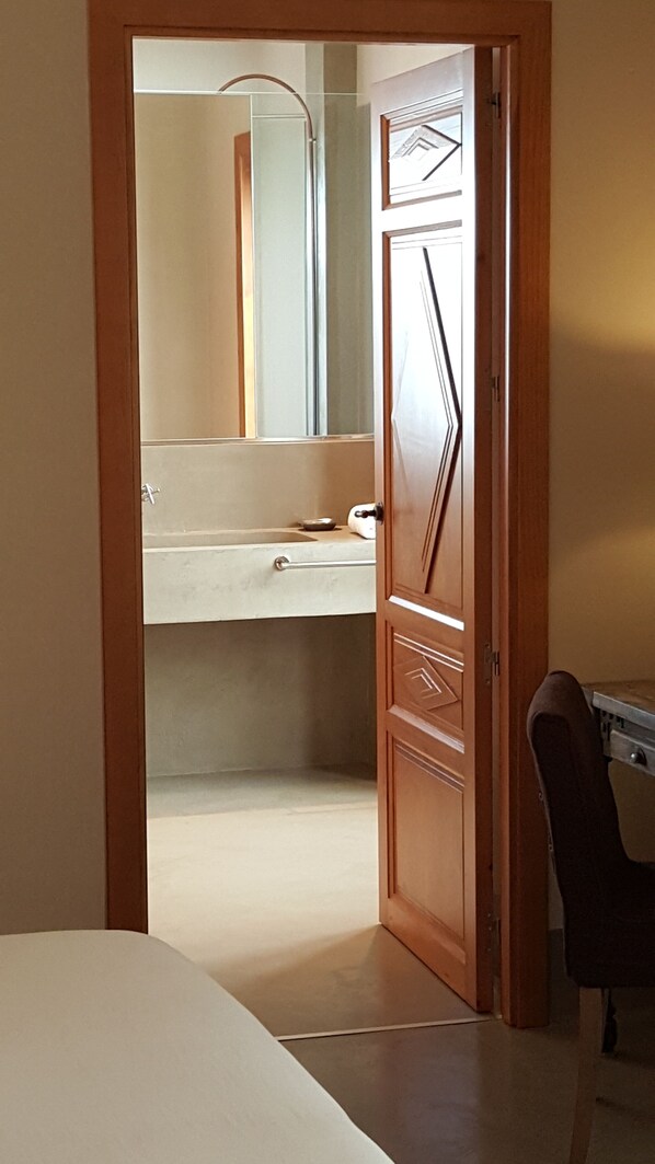 A narrow hallway leading to a bathroom with a mirror, sink, and towel rack. - Palacio Carvajal Girón (Plasencia)