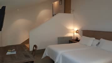 Une chambre à coucher comprenant un lit, une table de chevet, une lampe, un radiateur, une table en bois et une chaise.