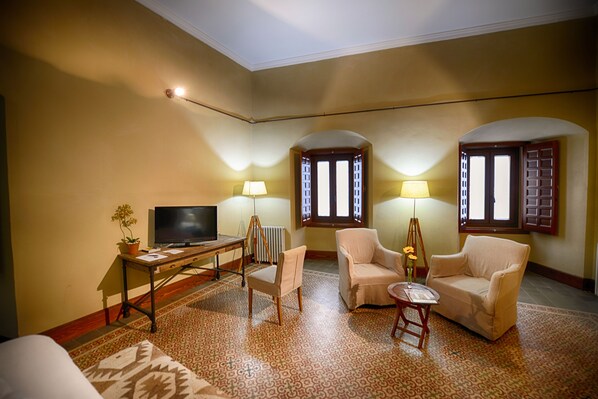Una sala de estar con televisor, dos sillones, una mesita y lámparas.