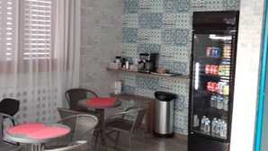 A small kitchenette with a coffee machine, a refrigerator stocked with beverages, and a patterned backsplash. - Citadel Hotel (Calais)