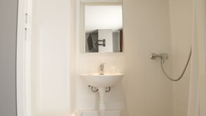 A small, white bathroom with a toilet, sink, and shower. - Citadel Hotel (Calais)