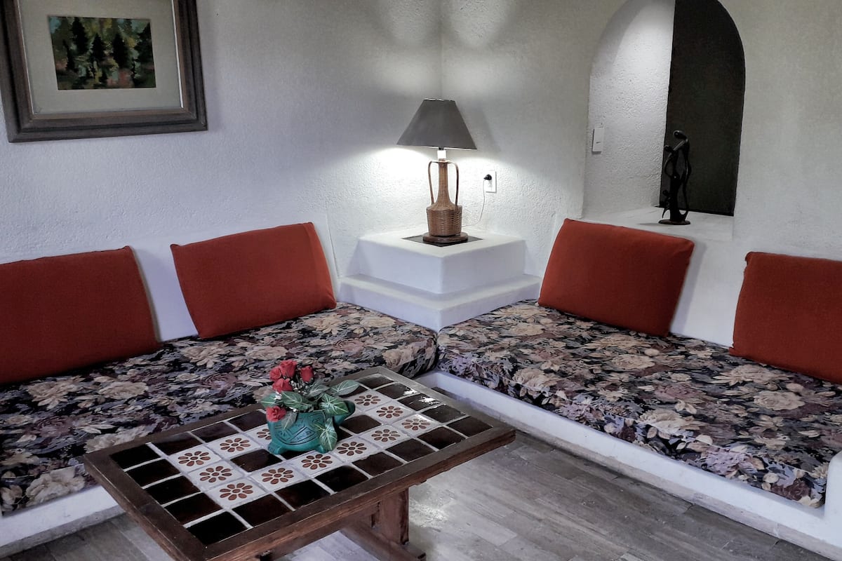 A cozy seating area with a sofa and a small table, a lamp, and a framed picture on the wall.