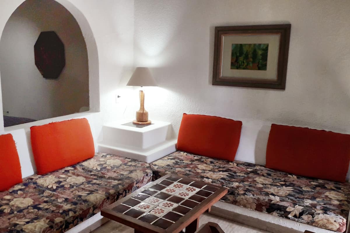 A room with a sofa set, a small table, a lamp, and a framed picture on the wall.