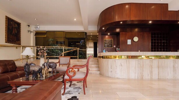 A lobby with a reception desk, a staircase, a seating area with a sofa and chairs, and a decorative elephant statue. - Apart Hotel San Martin (Lima)