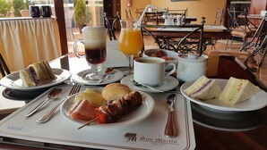 A breakfast table with various food items, a coffee cup, and a juice glass. - Apart Hotel San Martin (Lima)