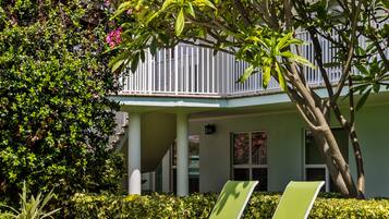 A poolside area with two white lounge chairs and a blue potted plant.