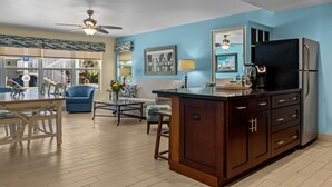 A modern kitchen with a central island, wooden cabinets, and a refrigerator. - Sun Dek Beach House (Boynton Beach)