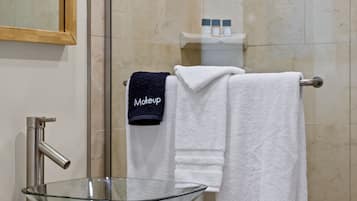 A bathroom with a glass bowl sink, a mirror, a towel rack with a white towel and a black towel labeled "Makeup".