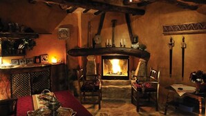 A cozy room with a stone fireplace, wooden furniture, and a table set for dining.