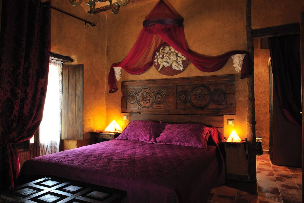 A bedroom with a large bed, a wooden headboard, and two bedside lamps.