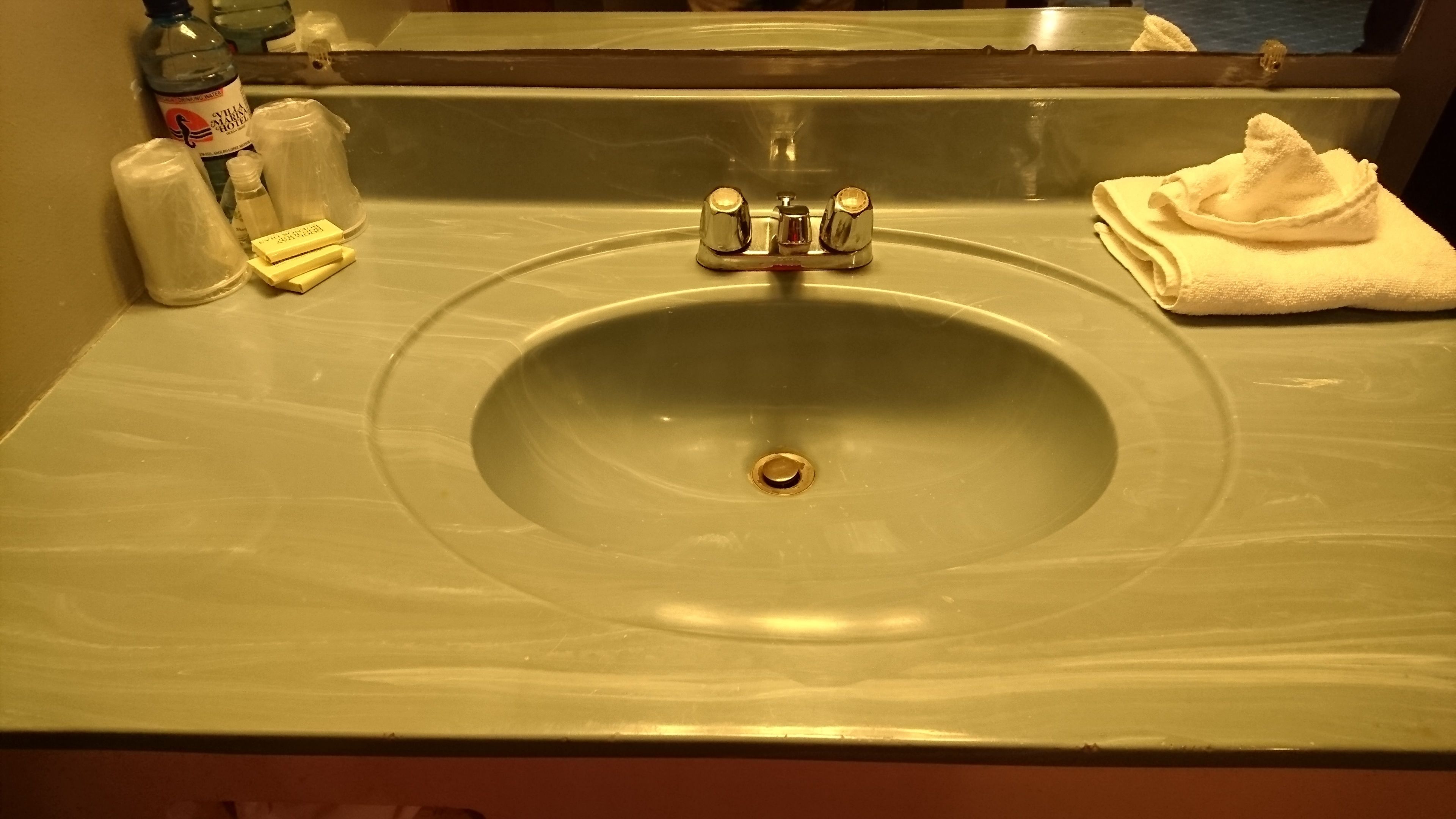 Un lavabo dans la salle de bain, avec un miroir au-dessus, une serviette et des articles de toilette posés sur le comptoir.