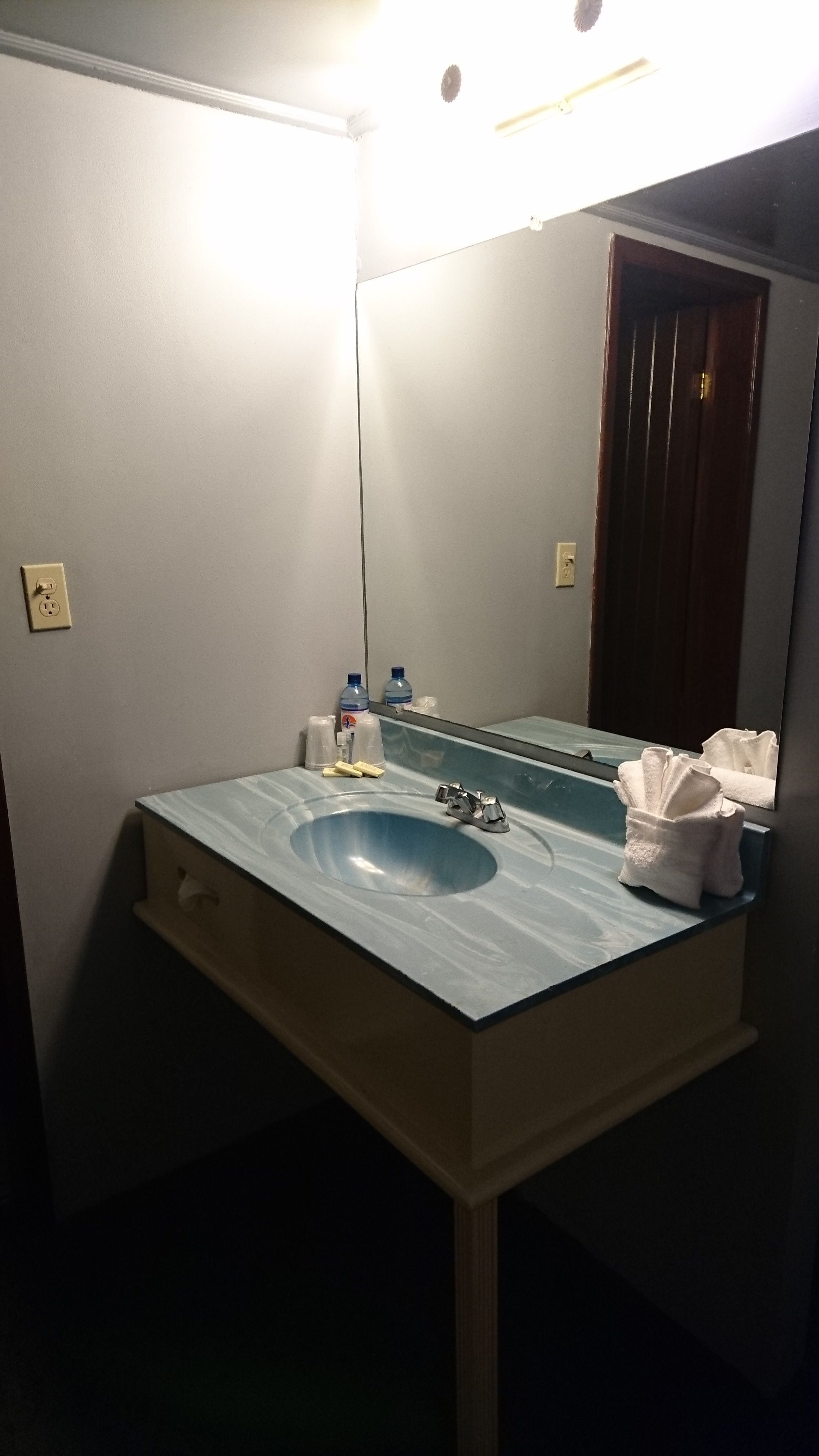 Un baño con un lavamanos azul, un espejo y un toallero.