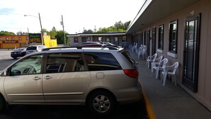 A motel with a row of white plastic chairs outside. - Maples Motel (Orillia)