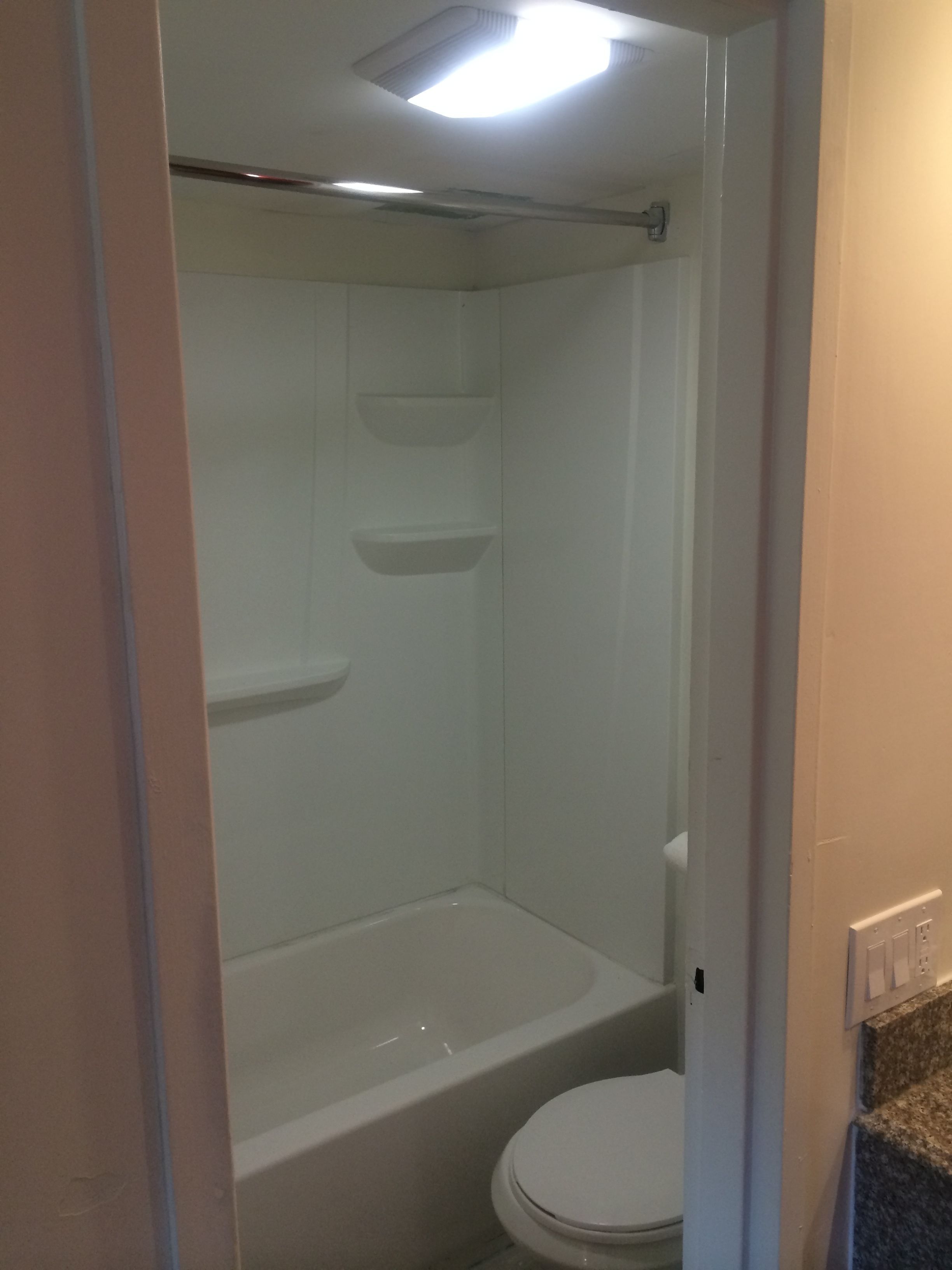 Een badkamer met een bad, toilet en douche.
