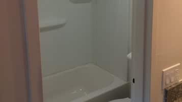 Een badkamer met een bad, toilet en douche.