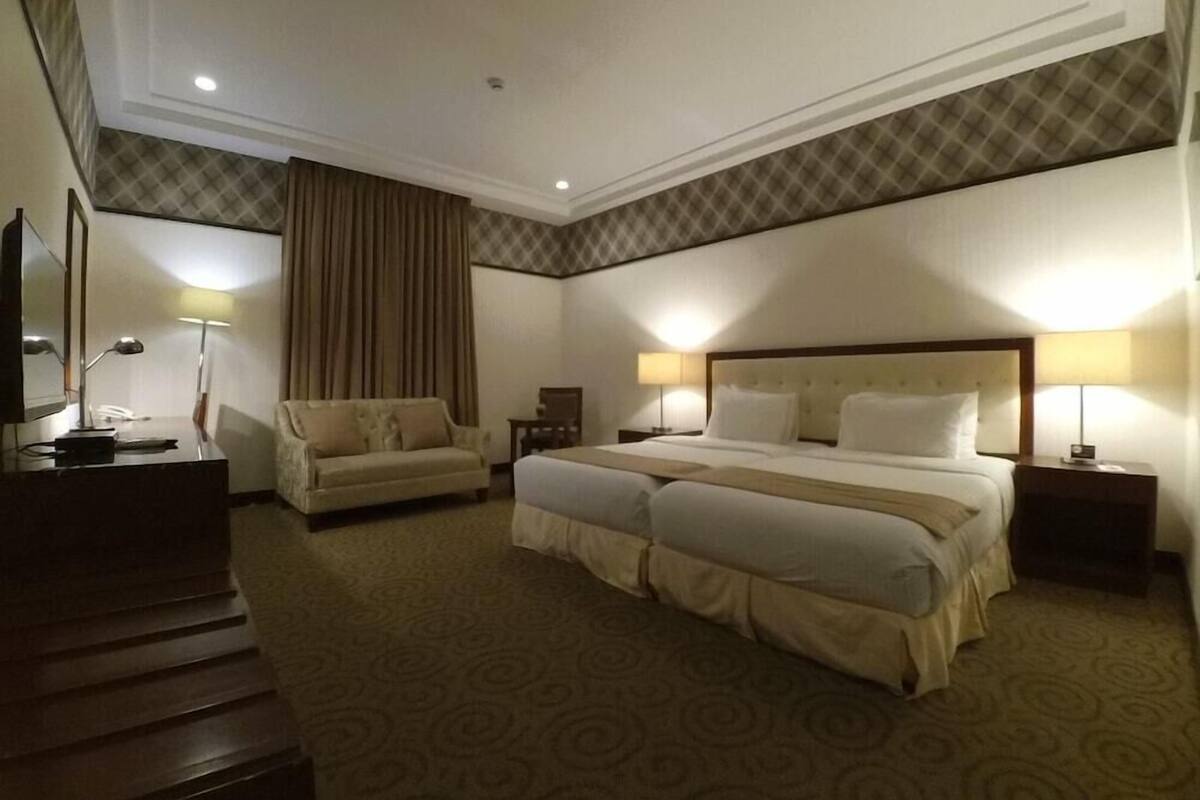Une chambre d’hôtel avec un grand lit, un canapé, un bureau avec une lampe et un téléviseur.