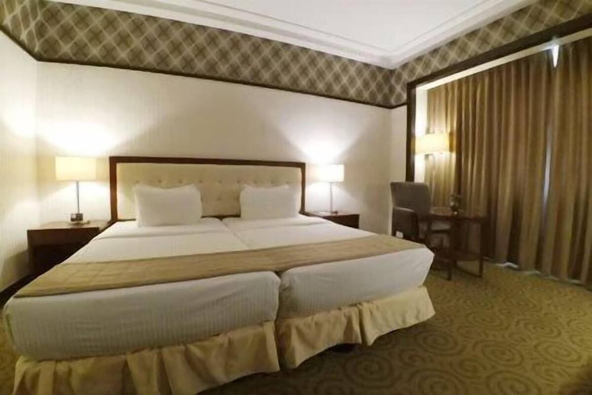 Une chambre d’hôtel avec un grand lit, deux tables de chevet avec des lampes, un bureau et une chaise.