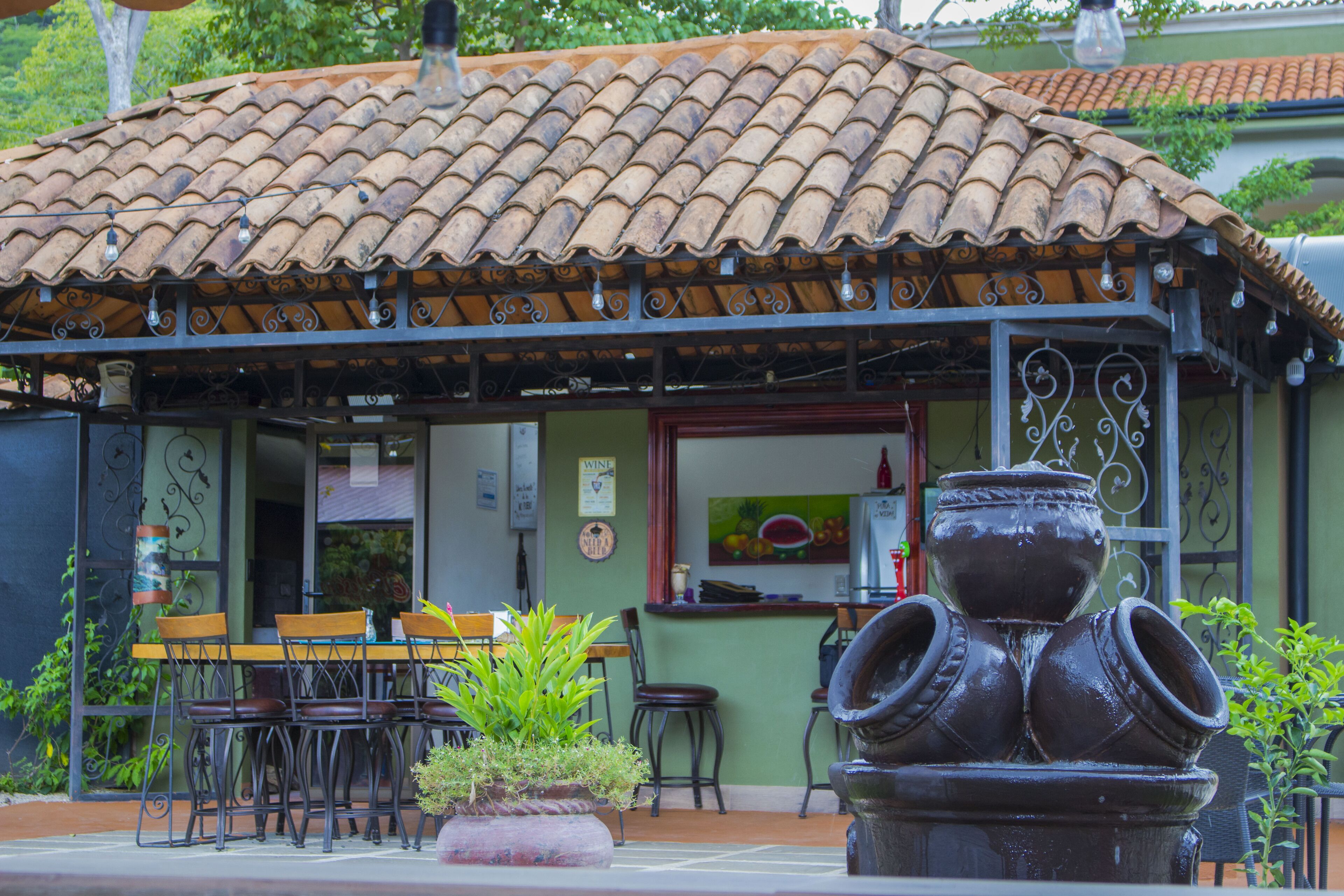A restaurant with outdoor seating, a tiled roof, and a decorative water feature.