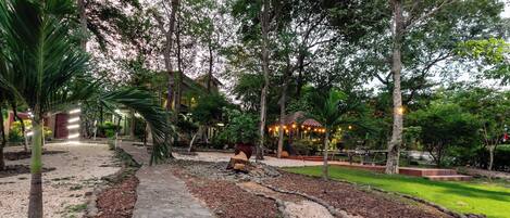 Un sentiero nel giardino, delimitato da pietre, circondato da alberi e un gazebo.