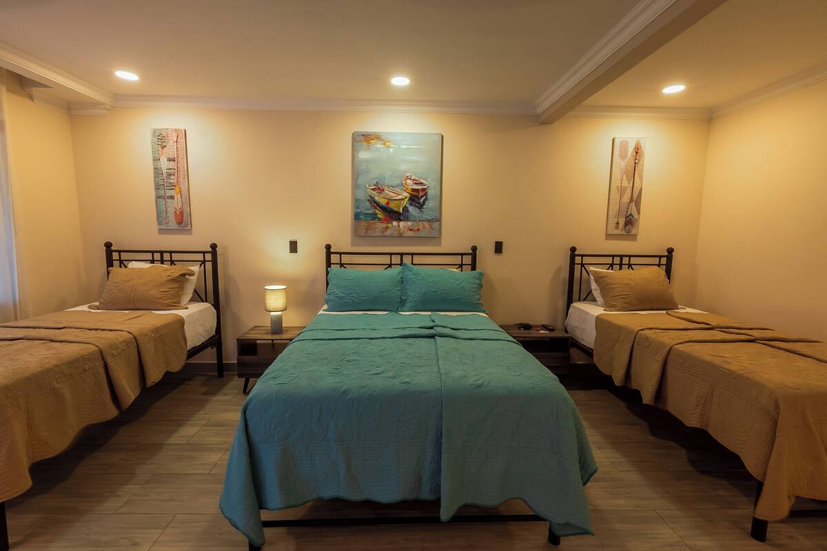 Ein Hotelzimmer mit zwei Einzelbetten, einem großen Bett und einem Gemälde an der Wand.