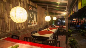 Un restaurant aux murs en bois, décoré de lanternes en papier suspendues et dont les tables sont recouvertes de nappes rouges.