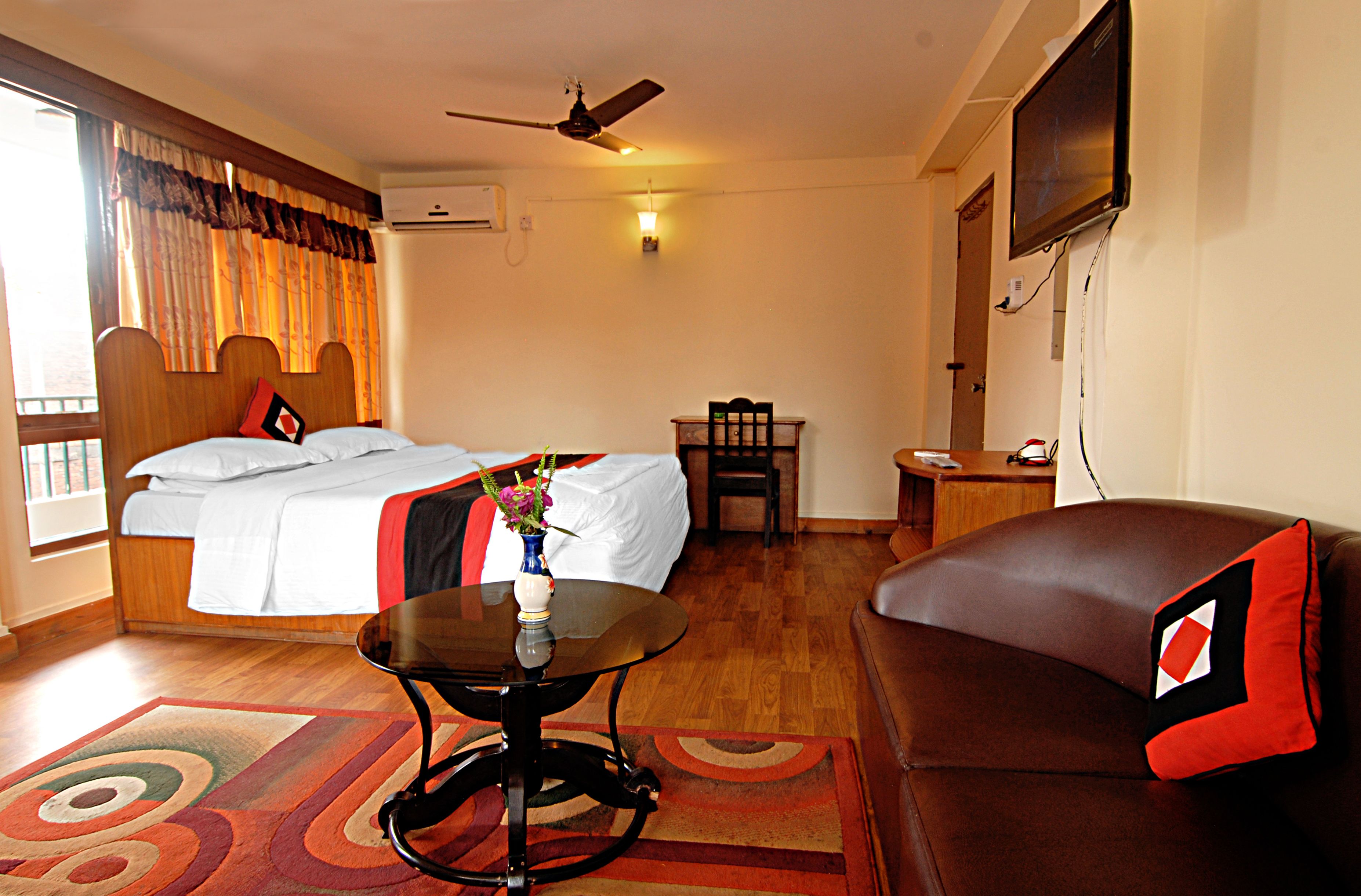 Una habitación de hotel con cama, sofá, mesa y televisor.