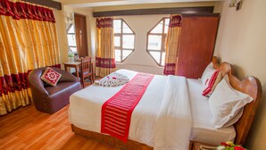 A neatly arranged hotel room with a large bed, a sofa, and a small table. - Pilgrims Guest House (Kathmandu)