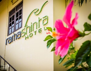 Un letrero de hotel con el nombre 'Rama Shinta Hotel' y una ventana con una reja decorativa.