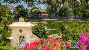 Ein friedlicher Garten mit Wasserspiel, üppigem Grün und einem kleinen weißen Pavillon.