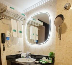 A bathroom with a sink, mirror, towel rack, and a hairdryer. - City Tower Hotel (Kuwait City)